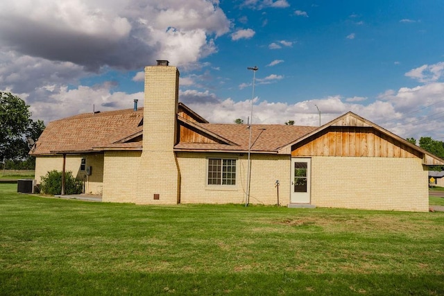 503 N Sheb Wooley Ave, Erick, OK 73645 - rear view of property featuring a chimney, a lawn, brick siding, and a shingled roof
