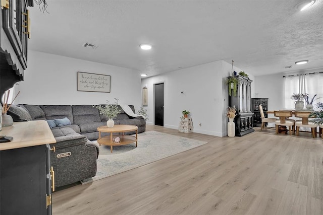 323 W 13th St, Snyder, OK 73566 - living area featuring light wood finished floors, a textured ceiling, and recessed lighting