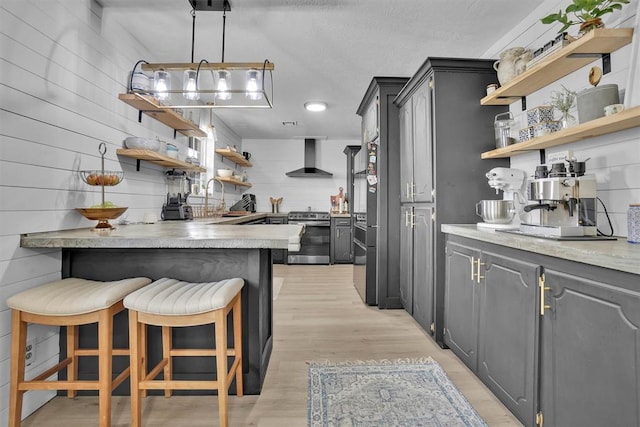 323 W 13th St, Snyder, OK 73566 - kitchen featuring open shelves, stainless steel range oven, wall chimney exhaust hood, and a peninsula