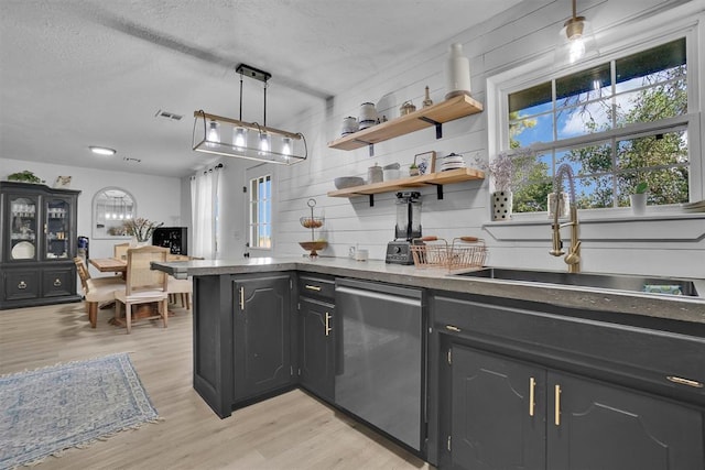 323 W 13th St, Snyder, OK 73566 - kitchen with dishwasher, light wood-style flooring, a textured ceiling, a peninsula, and dark countertops