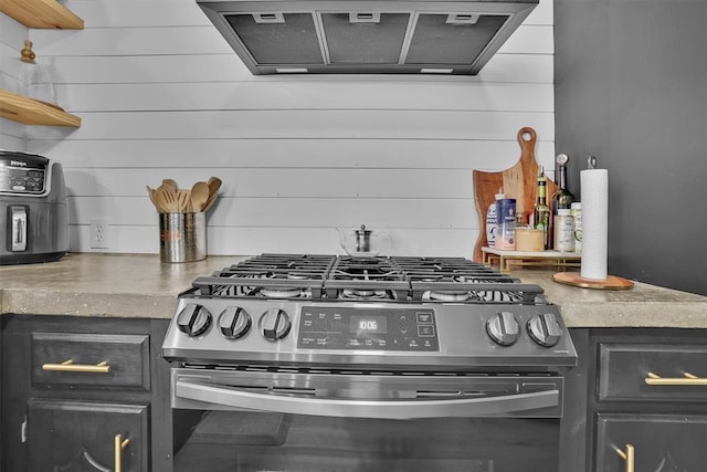323 W 13th St, Snyder, OK 73566 - kitchen view of gas stove, ventilation hood, open shelves, and wooden walls