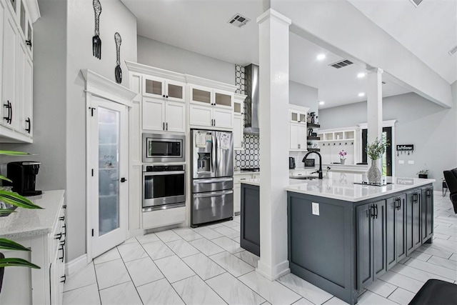 9228 E Cardinal Pl, Midwest City, OK 73130 - kitchen featuring stainless steel appliances, ornate columns, white cabinets, glass insert cabinets, and tasteful backsplash