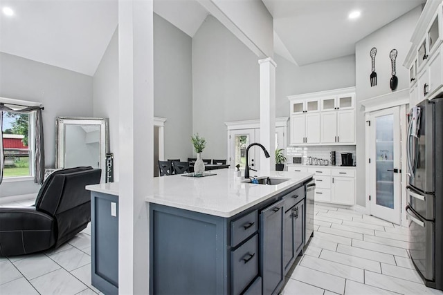 9228 E Cardinal Pl, Midwest City, OK 73130 - kitchen featuring stainless steel appliances, high vaulted ceiling, white cabinetry, glass insert cabinets, and decorative columns