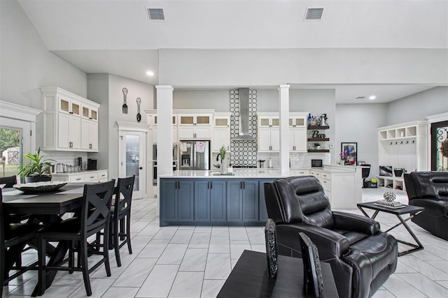9228 E Cardinal Pl, Midwest City, OK 73130 - kitchen featuring stainless steel fridge with ice dispenser, open floor plan, light countertops, backsplash, and ornate columns
