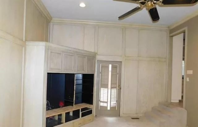 5720 Irvine Dr, Edmond, OK 73025 - unfurnished living room with ceiling fan, a decorative wall, and crown molding
