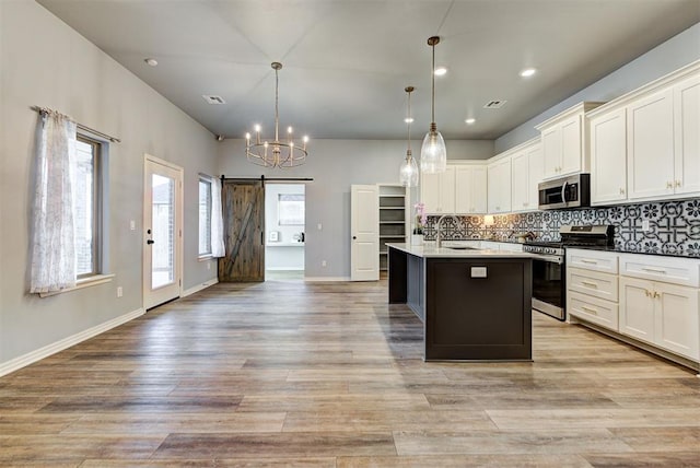 9021 NW 74th St, Yukon, OK 73099 - kitchen featuring appliances with stainless steel finishes, a barn door, backsplash, white cabinetry, and a chandelier
