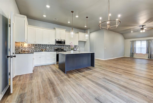 9021 NW 74th St, Yukon, OK 73099 - kitchen with stainless steel appliances, open floor plan, a ceiling fan, decorative backsplash, and a chandelier