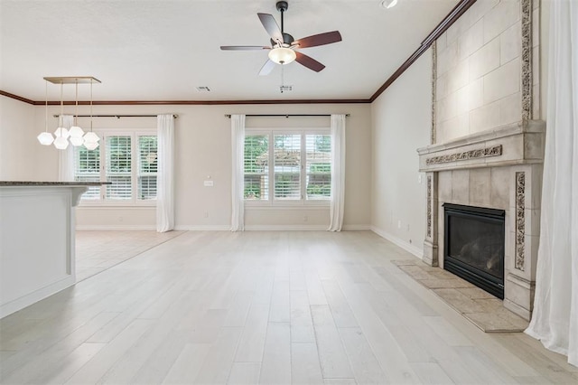 1008 Trisha Ln, Norman, OK 73072 - unfurnished living room with crown molding, a tiled fireplace, a ceiling fan, and light wood-style floors