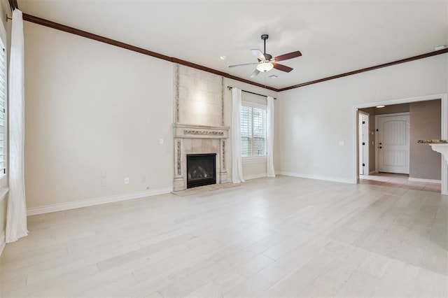 1008 Trisha Ln, Norman, OK 73072 - unfurnished living room featuring crown molding, a ceiling fan, a tiled fireplace, and light wood-type flooring