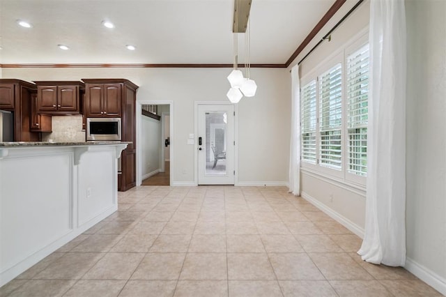 1008 Trisha Ln, Norman, OK 73072 - kitchen featuring stainless steel microwave, ornamental molding, dark stone countertops, decorative backsplash, and hanging light fixtures