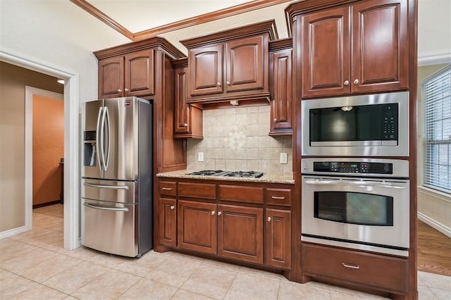 1008 Trisha Ln, Norman, OK 73072 - kitchen with stainless steel appliances, tasteful backsplash, light stone countertops, ornamental molding, and light tile patterned floors