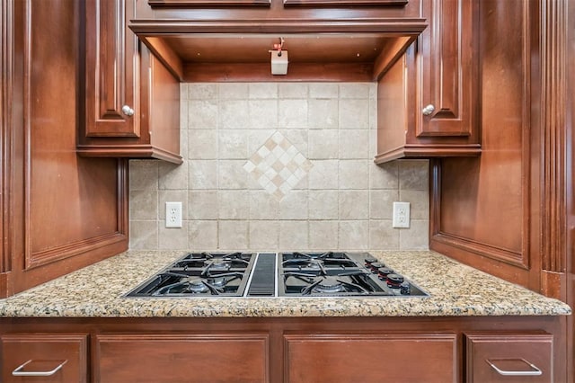 1008 Trisha Ln, Norman, OK 73072 - kitchen featuring stovetop with downdraft, decorative backsplash, light stone countertops, and brown cabinetry