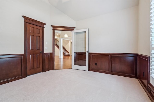 1008 Trisha Ln, Norman, OK 73072 - spare room featuring light carpet, wainscoting, vaulted ceiling, stairway, and plenty of natural light