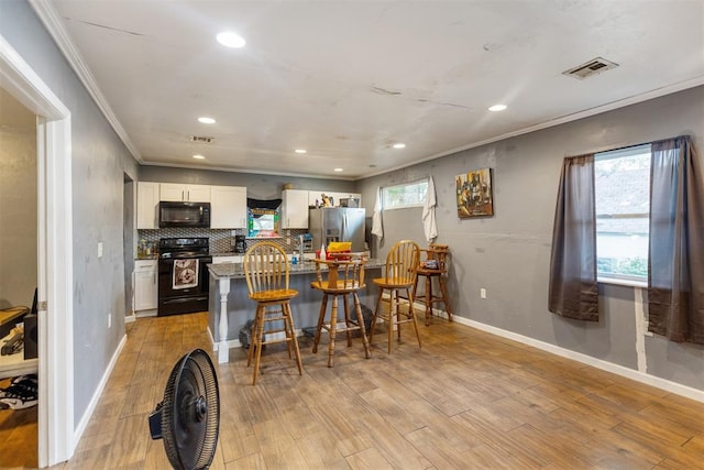 321 W 1st St, Wewoka, OK 74884 - kitchen featuring range with electric stovetop, black microwave, stainless steel fridge, ornamental molding, and a kitchen bar