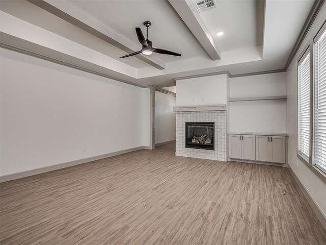 6609 NW 147th St, Oklahoma City, OK 73142 - unfurnished living room with a tray ceiling, a ceiling fan, light wood-type flooring, and a fireplace