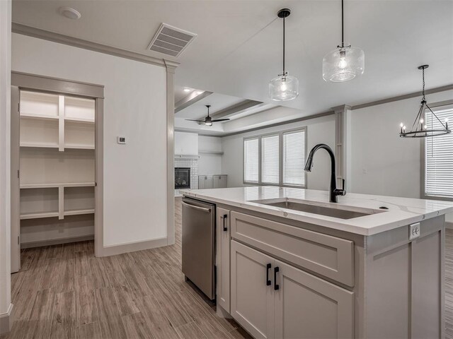 6609 NW 147th St, Oklahoma City, OK 73142 - kitchen with stainless steel dishwasher, a ceiling fan, a glass covered fireplace, a center island with sink, and hanging light fixtures