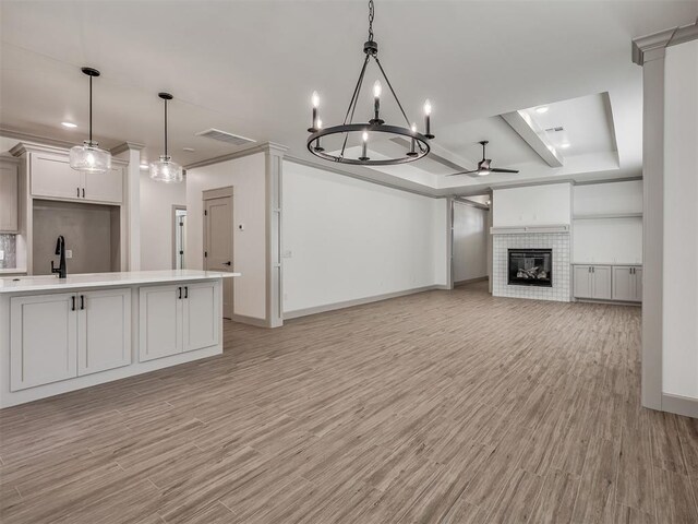 6609 NW 147th St, Oklahoma City, OK 73142 - kitchen featuring a ceiling fan, a tiled fireplace, light countertops, light wood-style flooring, and recessed lighting