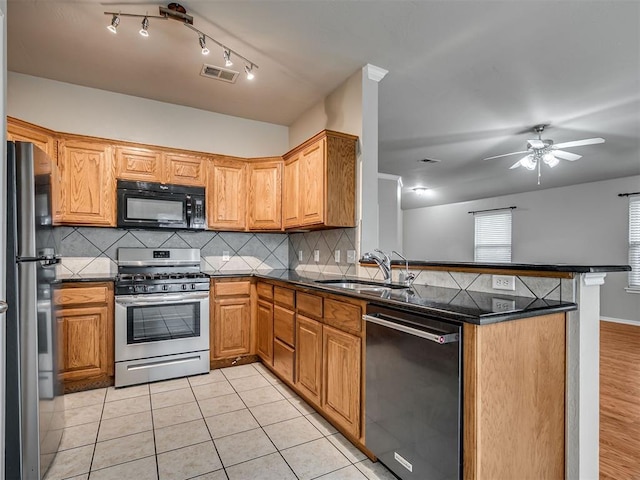 10808 Cheshire Ct, Yukon, OK 73099 - kitchen featuring appliances with stainless steel finishes, a peninsula, dark countertops, ceiling fan, and decorative backsplash