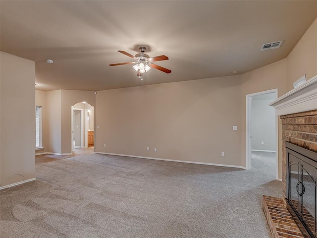 4513 SE 79th Ter, Oklahoma City, OK 73135 - unfurnished living room featuring a fireplace, light colored carpet, ceiling fan, and arched walkways