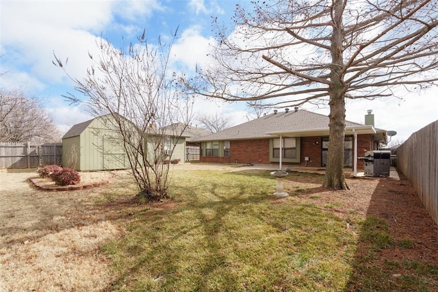 1709 Rocky Mountain Way, Edmond, OK 73003 - back of property featuring a fenced backyard, a storage unit, a chimney, and brick siding
