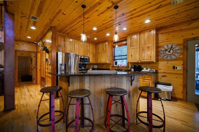 123 Hemlock Grove Rd, Hochatown, OK 74728 - kitchen featuring appliances with stainless steel finishes, wooden walls, light wood-style floors, dark countertops, and wood ceiling