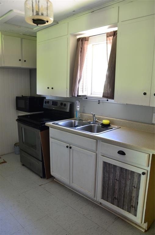 120 S Chickasaw Ave, Bartlesville, OK 74003 - kitchen featuring electric range, black microwave, light countertops, and white cabinets