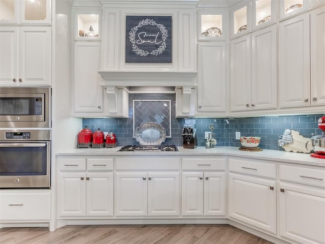 13308 NW 6th St, Yukon, OK 73099 - kitchen featuring stainless steel appliances, white cabinets, decorative backsplash, light wood finished floors, and glass insert cabinets