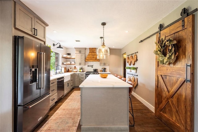 19277 E 1220th Rd, Sayre, OK 73662 - kitchen with stainless steel appliances, a barn door, custom exhaust hood, dark wood-style flooring, and a kitchen island