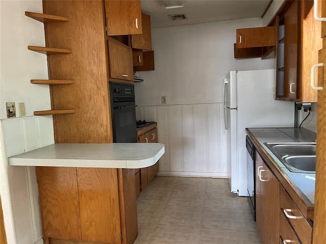 1333 Reid St, Seminole, OK 74868 - kitchen with black appliances, open shelves, brown cabinets, a peninsula, and a wainscoted wall