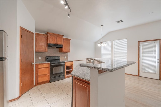 2412 NW 164th Ter, Edmond, OK 73013 - kitchen with black range with electric cooktop, freestanding refrigerator, vaulted ceiling, under cabinet range hood, and hanging light fixtures