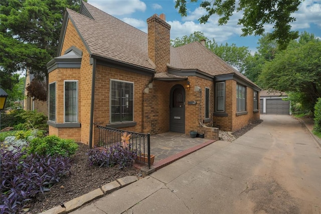 217 NW 30th St, Oklahoma City, OK 73118 - english style home with brick siding, roof with shingles, a chimney, and an outbuilding