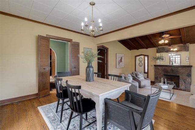 217 NW 30th St, Oklahoma City, OK 73118 - dining space with a stone fireplace, a chandelier, wood finished floors, crown molding, and ceiling fan