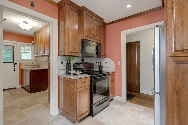 217 NW 30th St, Oklahoma City, OK 73118 - kitchen with black appliances, tasteful backsplash, light stone counters, brown cabinetry, and ornamental molding