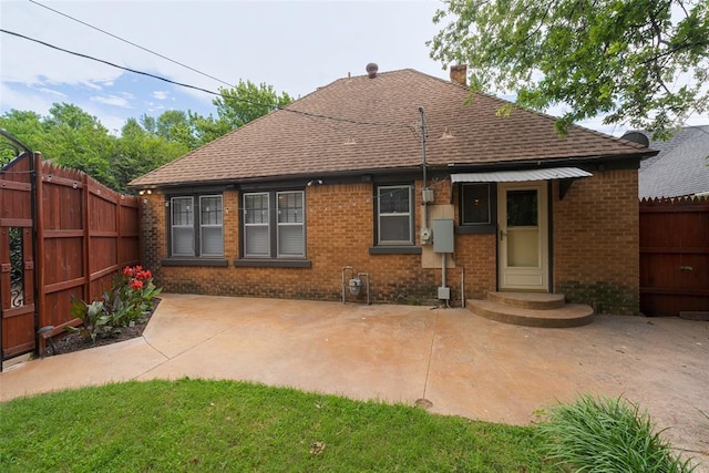217 NW 30th St, Oklahoma City, OK 73118 - back of property featuring brick siding, roof with shingles, a chimney, and a patio