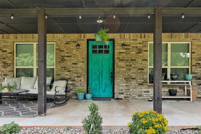 14716 Turkey Hills Rd, Newalla, OK 74857 - view of exterior entry featuring outdoor lounge area, brick siding, and covered porch