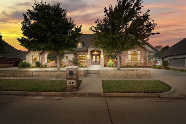 2229 Rockbridge Ct, Yukon, OK 73099 - view of property hidden behind natural elements with french doors, stone siding, and a lawn