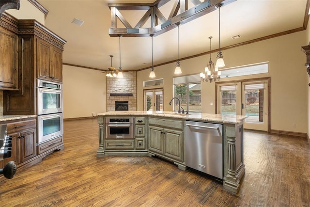 2229 Rockbridge Ct, Yukon, OK 73099 - kitchen with appliances with stainless steel finishes, a fireplace, dark wood-type flooring, a chandelier, and crown molding