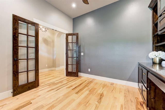 7600 Walk In The Park Dr, Edmond, OK 73034 - empty room featuring french doors, arched walkways, light wood finished floors, and a ceiling fan
