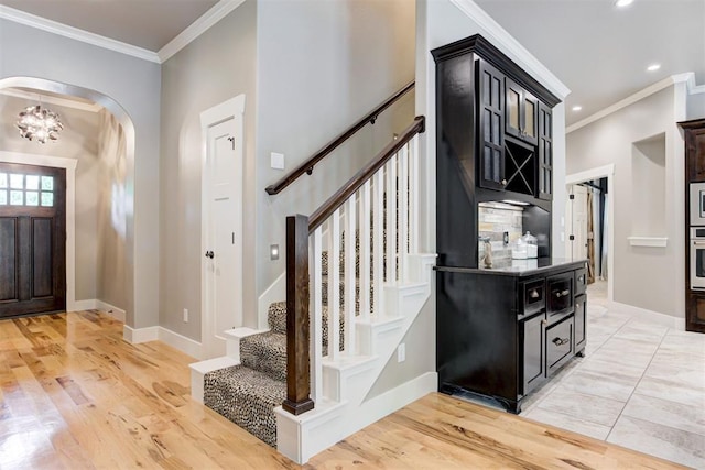 7600 Walk In The Park Dr, Edmond, OK 73034 - entryway featuring ornamental molding, arched walkways, stairway, light wood-type flooring, and a chandelier
