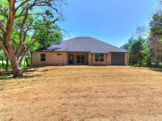 9070 Oak Tree Cir, Edmond, OK 73025 - rear view of house featuring a garage, a lawn, and roof with shingles