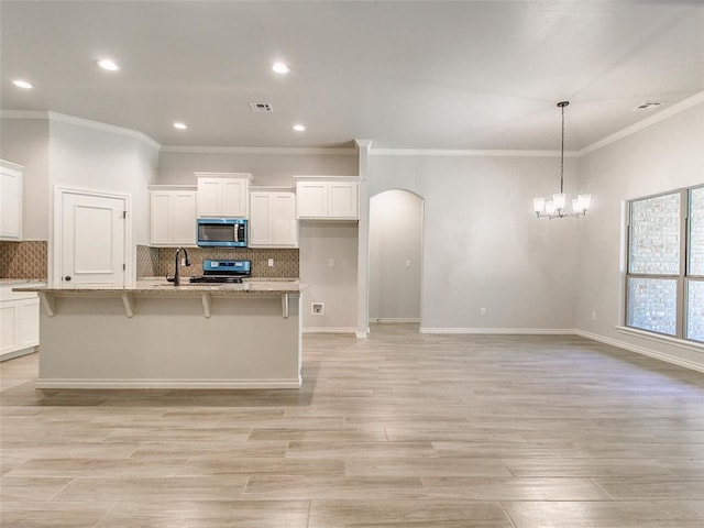 9070 Oak Tree Cir, Edmond, OK 73025 - kitchen featuring appliances with stainless steel finishes, arched walkways, a chandelier, crown molding, and white cabinets