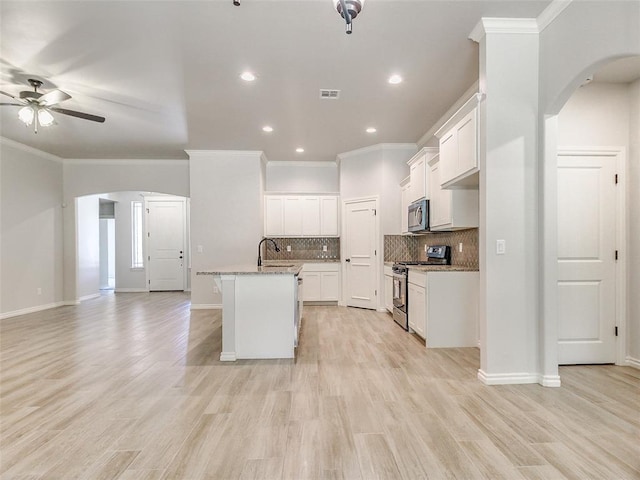 9070 Oak Tree Cir, Edmond, OK 73025 - kitchen with stainless steel appliances, arched walkways, a ceiling fan, open floor plan, and crown molding