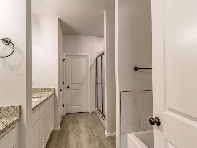 9070 Oak Tree Cir, Edmond, OK 73025 - full bathroom featuring wood finished floors, vanity, a bath, and a stall shower
