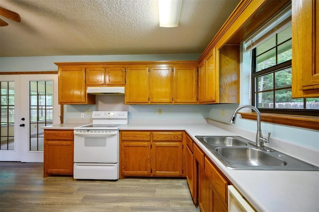 1001 Norris Ave, Broken Bow, OK 74728 - kitchen featuring white range with electric cooktop, under cabinet range hood, a textured ceiling, brown cabinetry, and light countertops