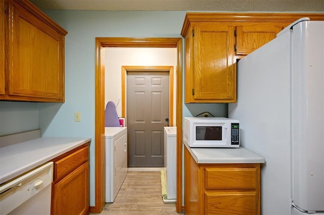 1001 Norris Ave, Broken Bow, OK 74728 - kitchen with white appliances, washing machine and dryer, light wood-style floors, and light countertops