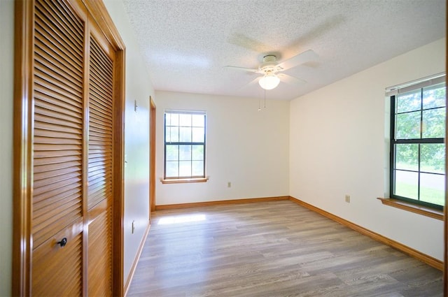 1001 Norris Ave, Broken Bow, OK 74728 - unfurnished bedroom featuring multiple windows, a closet, light wood-style floors, a textured ceiling, and a ceiling fan