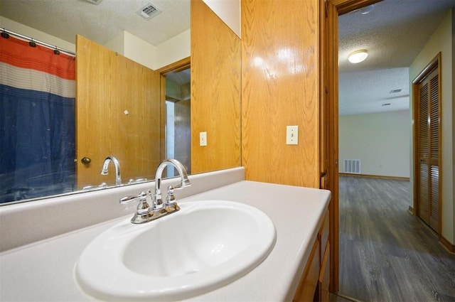 1001 Norris Ave, Broken Bow, OK 74728 - bathroom with a textured ceiling, wood finished floors, and vanity