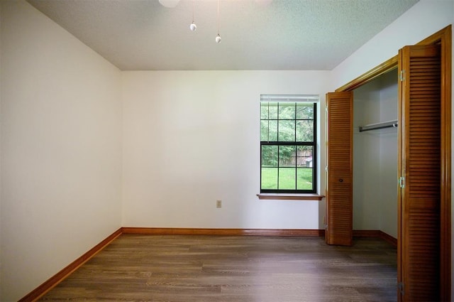 1001 Norris Ave, Broken Bow, OK 74728 - unfurnished bedroom with wood finished floors, a closet, and a textured ceiling