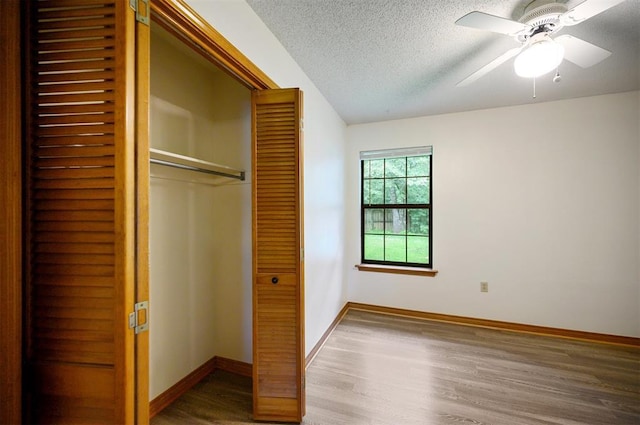 1001 Norris Ave, Broken Bow, OK 74728 - unfurnished bedroom featuring a closet, wood finished floors, a textured ceiling, and a ceiling fan