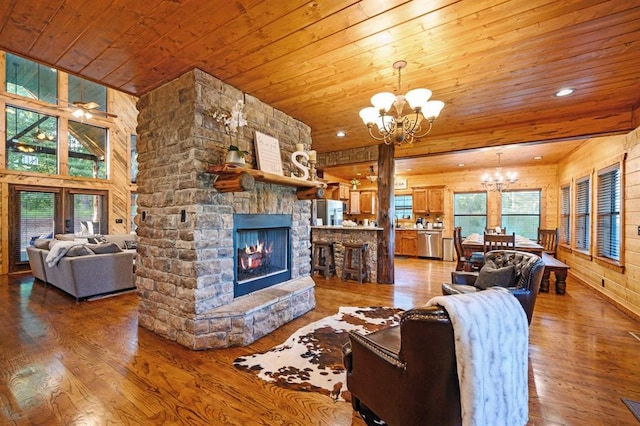 25 Paint Horse Cir, Broken Bow, OK 74728 - living room with a chandelier, wooden ceiling, wood-type flooring, wood walls, and a stone fireplace